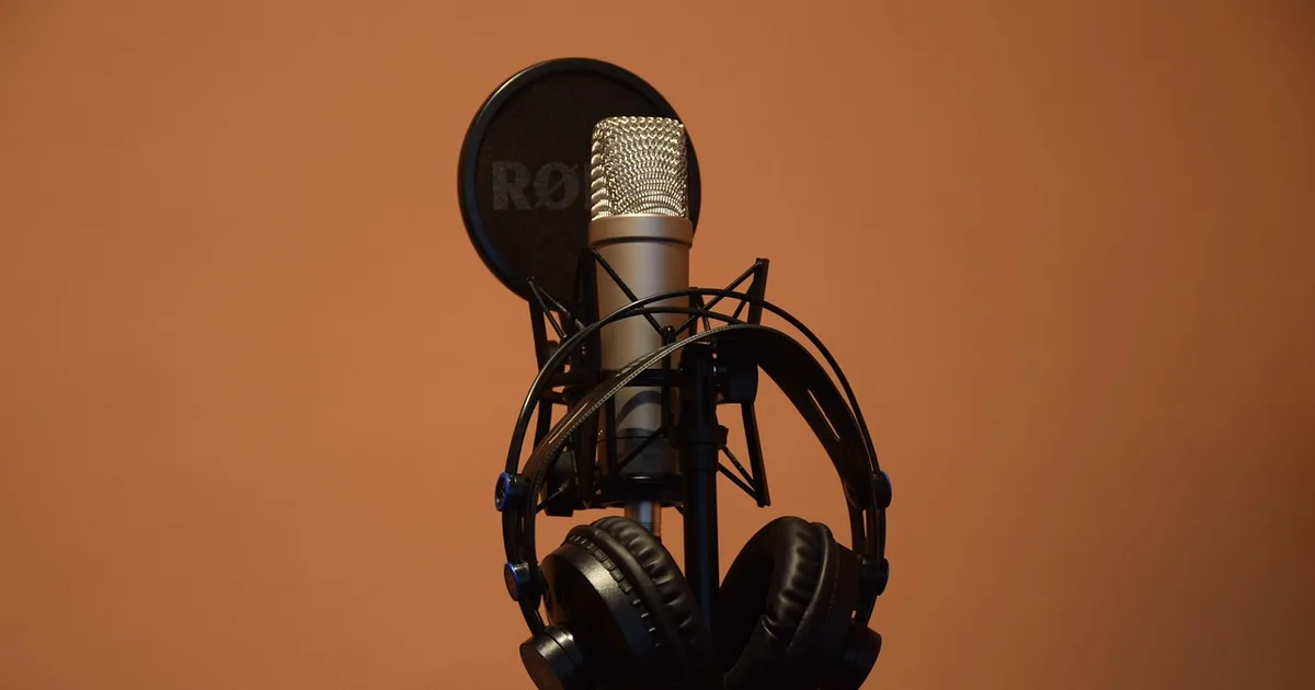 Podcast microphone and headphones on a desk in a recording studio