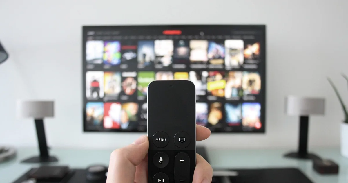 Living room television with a remote control showing a live channel guide